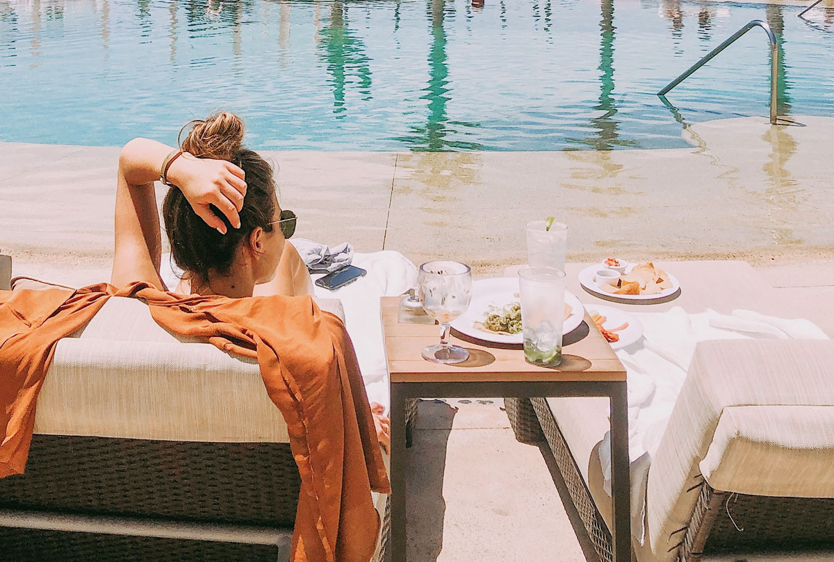 woman relaxes by tranquil hotel pool 